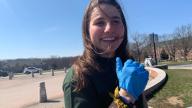 A person with long hair wearing a blue glove and smiling.