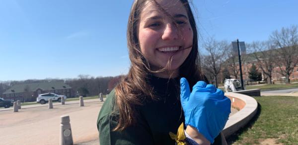 A person with long hair wearing a blue glove and smiling.​
