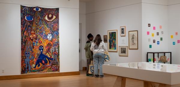 exhibit floor with pictures on the walls and two people standing in front of them