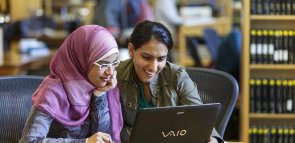 library two women sitting at table with laptop
