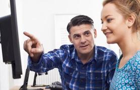 male and femal student looking at PC monitor